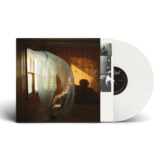 A white vinyl record partially pulled from its album sleeve, showing the cover art of Beck in a room with warm sunlight